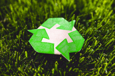 recycle sign hand drawn on cardboard resting on perfect green grass from private lawn, shot under strong sunlightの写真素材