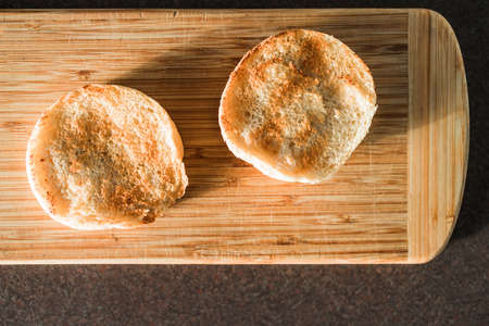 freshly toaste English muffins on cutting board shot under harsh sunlight, concept of simple natural...