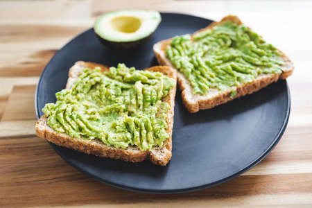 basic plant-based smashed avocado toast with half avocado next to it, healthy vegan food recipes