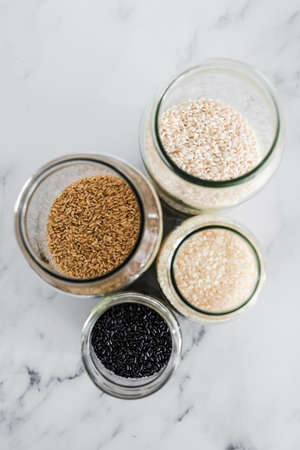 pantry jars with different types of rice including black brown arborio and sushi rice, concept of...