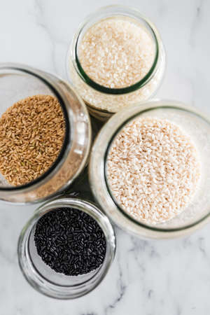 pantry jars with different types of rice including black brown arborio and sushi rice, concept of simple staple ingredientsの写真素材