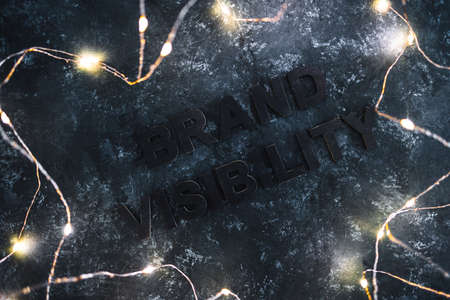 Brand Visibility text barely visible on dark background with fairy lights around it, concept of businesses struggling to become popularの写真素材