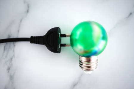 concept of clean green energy, electric plug next to green lightbulbの写真素材