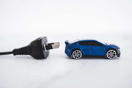 concept of electric or hybrid vehicles, blue toy car with plug behing itの写真素材