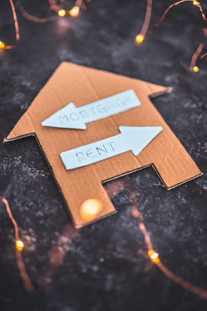house icon with mortgage or rent signs pointing in opposite directions on dark background with LED...