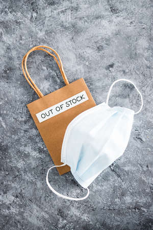 Out of Stock text on top of shopping bag with surgical mask, concept of supply chain shortages and...