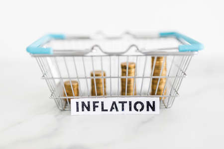 prices going up and rising inflation concept with text in front of shopping basket with growing...