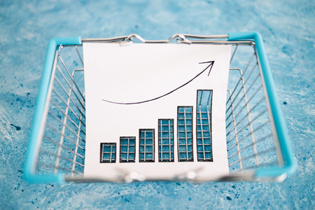 inflation and post pandemic economical recession conceptual image, cutout graph showing prices going up inside of shopping basket on blue backgroundの写真素材