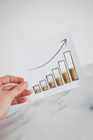 inflation increasing or investments going well conceptual image, cutout graph with stats going up and stacks of coins visible through itの写真素材