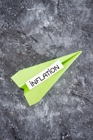 inflation text on paper plane going up with stats graphs, concept of economic struggles after the pandemicの写真素材