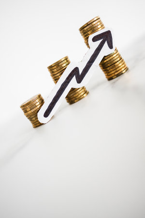 growing stacks of coins with arrow going up, concept of prices becoming more expensive or savings and compound interests increasingの写真素材