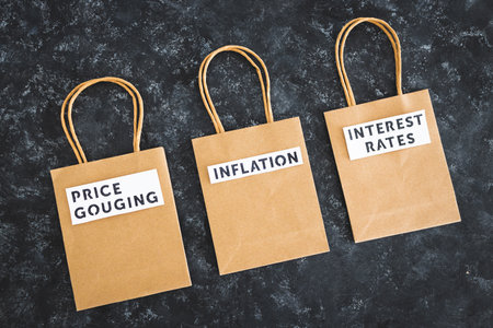 Inflation Interest Rates and Price Gouging texts on paper shopping bags on dark background, symbol of excessive pricingの写真素材