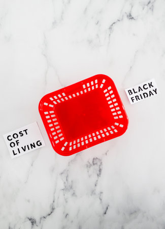 Cost of living vs Black friday conceptual image with red empty shopping basket in between opposite...