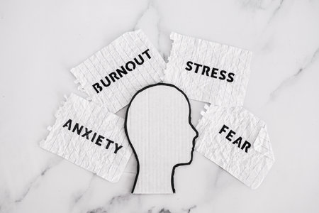 mental health and reaching out for help conceptual image, cardboard head surrounded by scrunched up paper with texts Anxiety Burnout Fear and Stressの写真素材