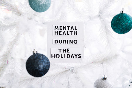 mental health during the holidays text on festive Christmas tree, concept of managing overwhelm and...