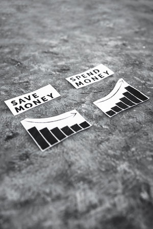 save money vs spend money texs side by side with graphs showing wealth going up or down, concept of...