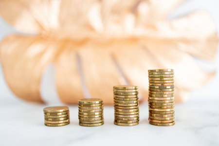 stacks of progressively increasing coins in front of golden leaf, concept of increasing your savings...