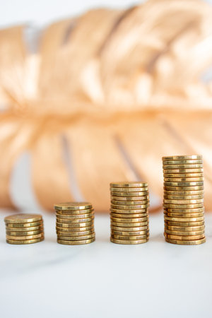 stacks of progressively increasing coins in front of golden leaf, concept of increasing your savings...