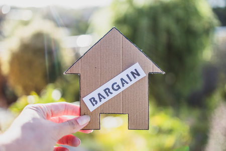 Bargain label on cardboard house in front of backyard bokeh, concept of finding a dream property and real estate market affordabilityの写真素材