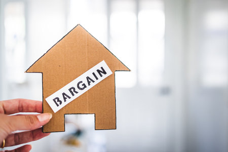 finding a dream property and real estate market affordability concept, Bargain label on cardboard house in front of entry doorの写真素材