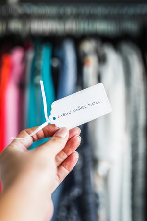 New Collection sign held in front of rack full of clothes, concept of fashion brands and competitionの写真素材