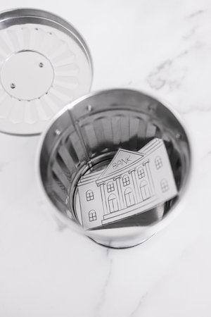 insolvency and banks closing down concept, bank made of paper thrown inside miniature garbage binの写真素材