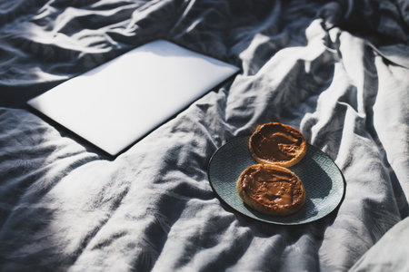 breafast peanut butter English muffins on bed doona with laptop next to them, concept of simple morning habitsの写真素材