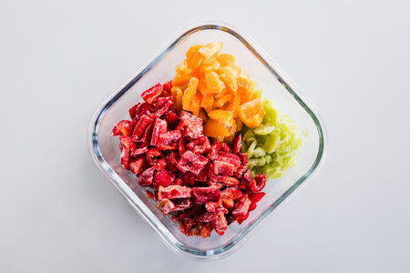 frozen chopped up bell peppers in red green and yellow varieties in glass container, concept of simple natural healthy ingredientsの写真素材