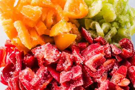 frozen chopped up bell peppers in red green and yellow varieties in glass container, concept of simple natural healthy ingredientsの写真素材