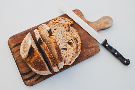 dark rye bread cut into slices on rustic chopping board,  concept of simple natural healthy...
