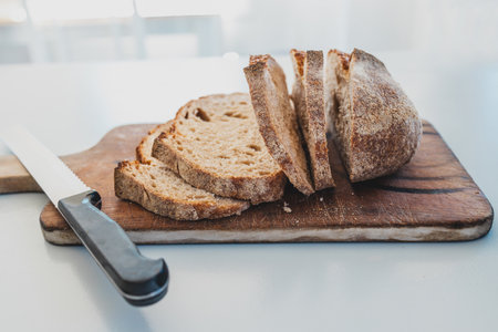 dark rye bread cut into slices on rustic chopping board,  concept of simple natural healthy ingredientsの写真素材