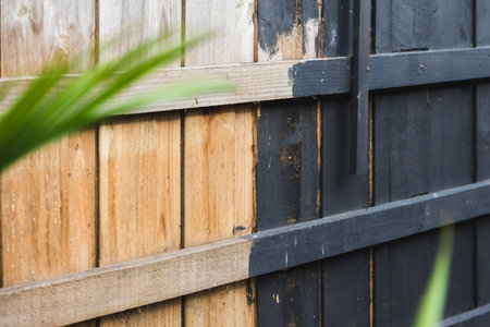 half painted backyard retaining wall or fence, charcoal vs bare wood, home improvement and renovation conceptの写真素材