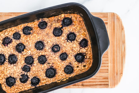 baked oats with blueberries in black oven tray on cutting board, healthy vegan food recipesの写真素材