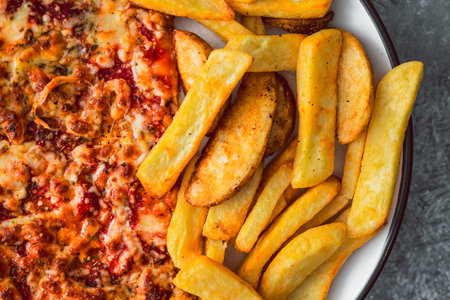 plate with half pizza half chips, concept of fast food or unhealthy caloric foodの写真素材