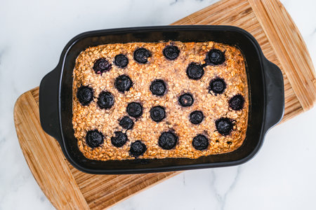 baked oats with blueberries in black oven tray on cutting board, healthy vegan food recipesの写真素材