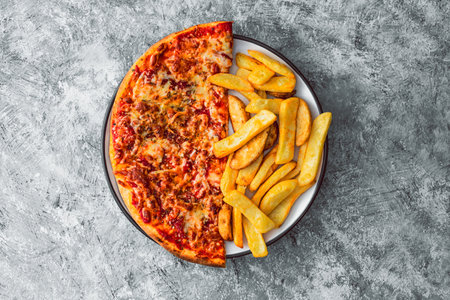 plate with half pizza half chips, concept of fast food or unhealthy caloric foodの写真素材