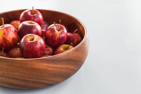 plenty of red apples in big wooden fruit bowl on kitchen countertop, concept of simple natural...