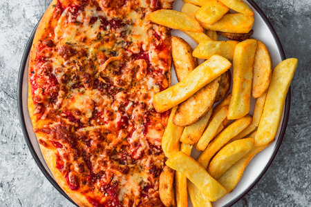 plate with half pizza half chips, concept of fast food or unhealthy caloric foodの写真素材