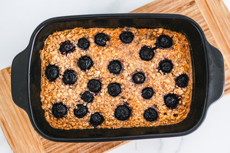 baked oats with blueberries in black oven tray on cutting board, healthy vegan food recipesの写真素材