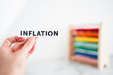 cost of living and recession conceptual image, hand holding Inflation sign in front of colorful abacusの写真素材