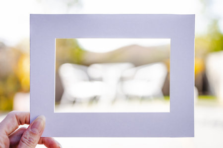 hand holding empty frame in front of lush tropical suburban backyard bokeh, add you text, frame...