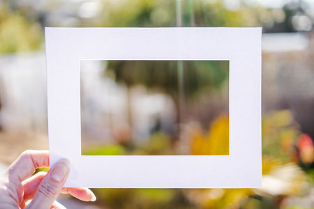 hand holding empty frame in front of lush tropical suburban backyard bokeh, add you text, frame mockupの写真素材