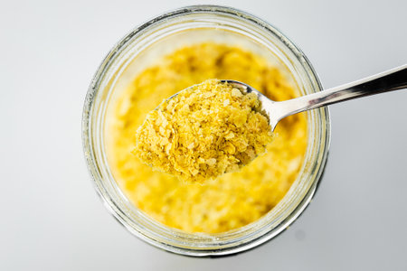 pantry staple close-up, spoonful of nutritional yeast over clear glass jar shot from above, daily ingredientsの写真素材