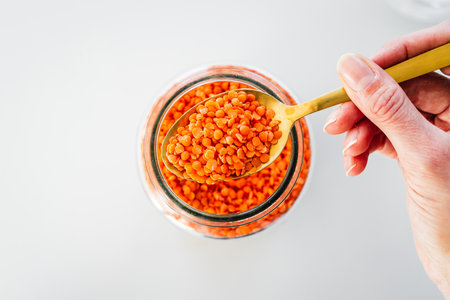 pantry staple close-up, spoonful of red lentils over clear glass jar shot from above, daily ingredientsの写真素材
