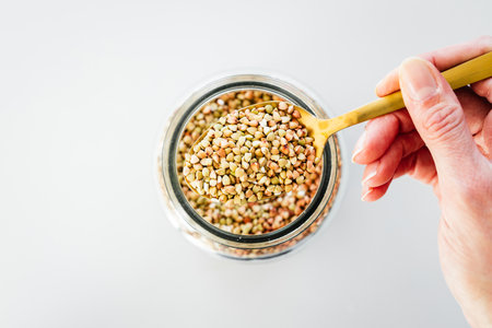 pantry staple close-up, spoonful of buckwheat over clear glass jar shot from above, daily ingredientsの写真素材