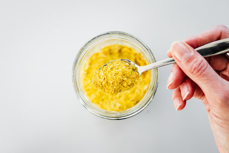 pantry staple close-up, spoonful of nutritional yeast over clear glass jar shot from above, daily ingredientsの写真素材