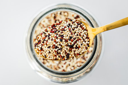 pantry staple close-up, spoonful of tricolor quinoa over clear glass jar shot from above, daily...