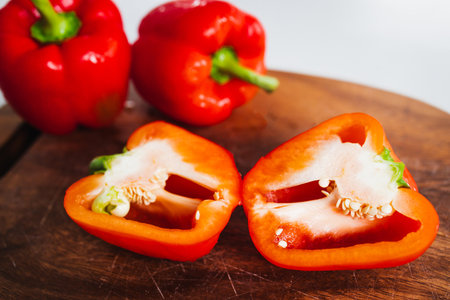 fresh red bell peppers on wooden chopping board, concept of simple natural healthy ingredientsの写真素材