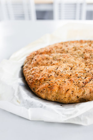 round homemade focaccia bread with rosemary and salt flakes straight out of the ovenの写真素材