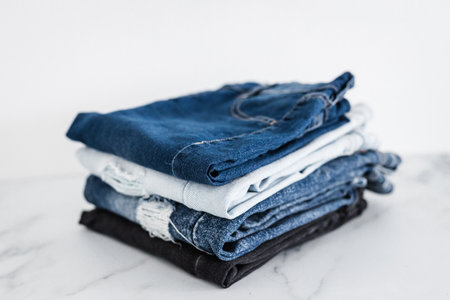pile of jeans in different color denim fabric neatly folded and piled up on minimalistic backgroundの写真素材